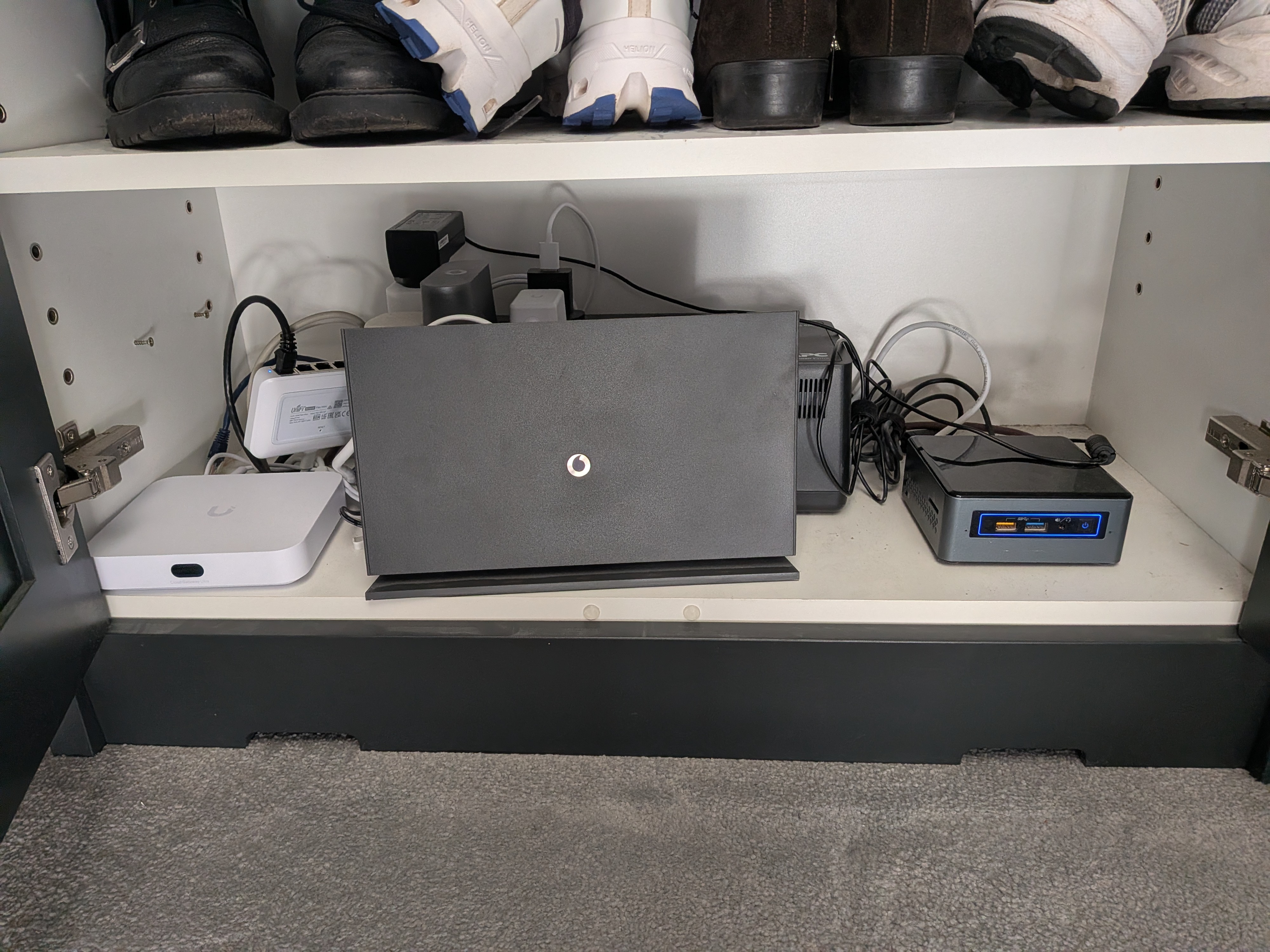 Bedroom wardrobe showing Vodafone modem, UCG Ultra router, and Pacific NUC